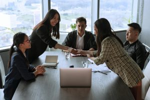 Angel investors and team member shaking hands in a meeting room.